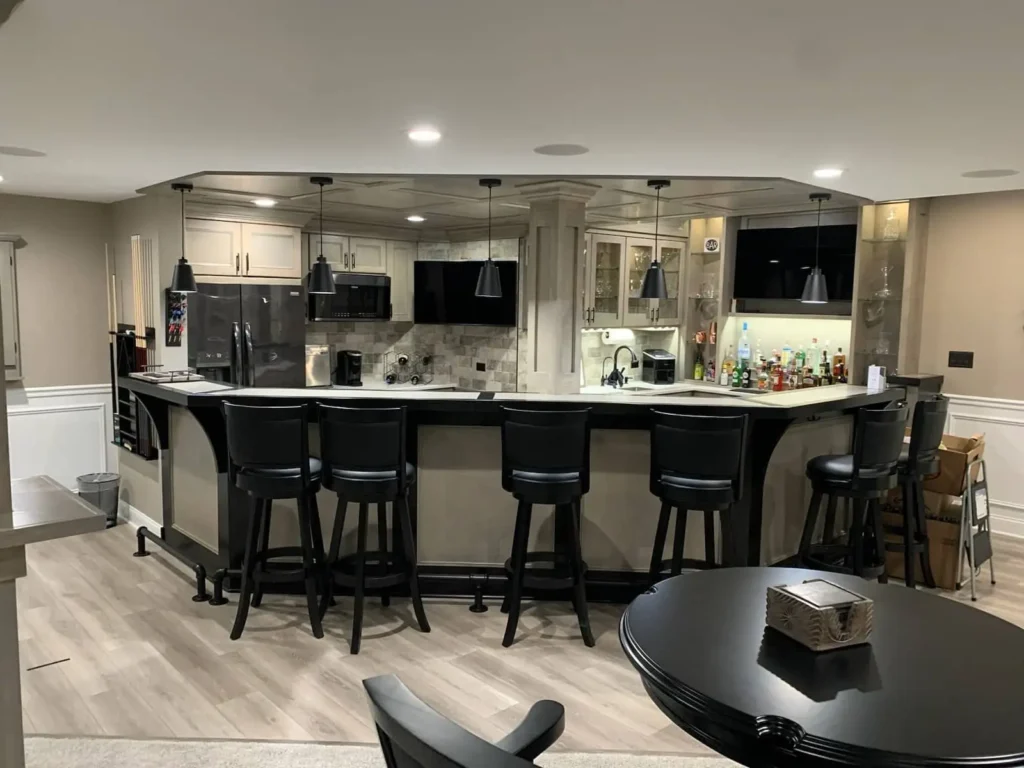 Finished basement bar with gray cabinets, black bar stools, and kitchen amenities in Geneva, Illinois home