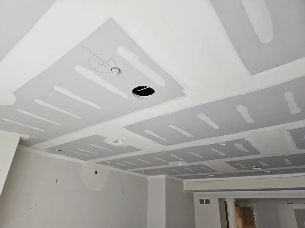 Professional drywall ceiling installation featuring precision taping work, recessed lighting preparation, and detailed coffered ceiling design in Wilmette luxury home