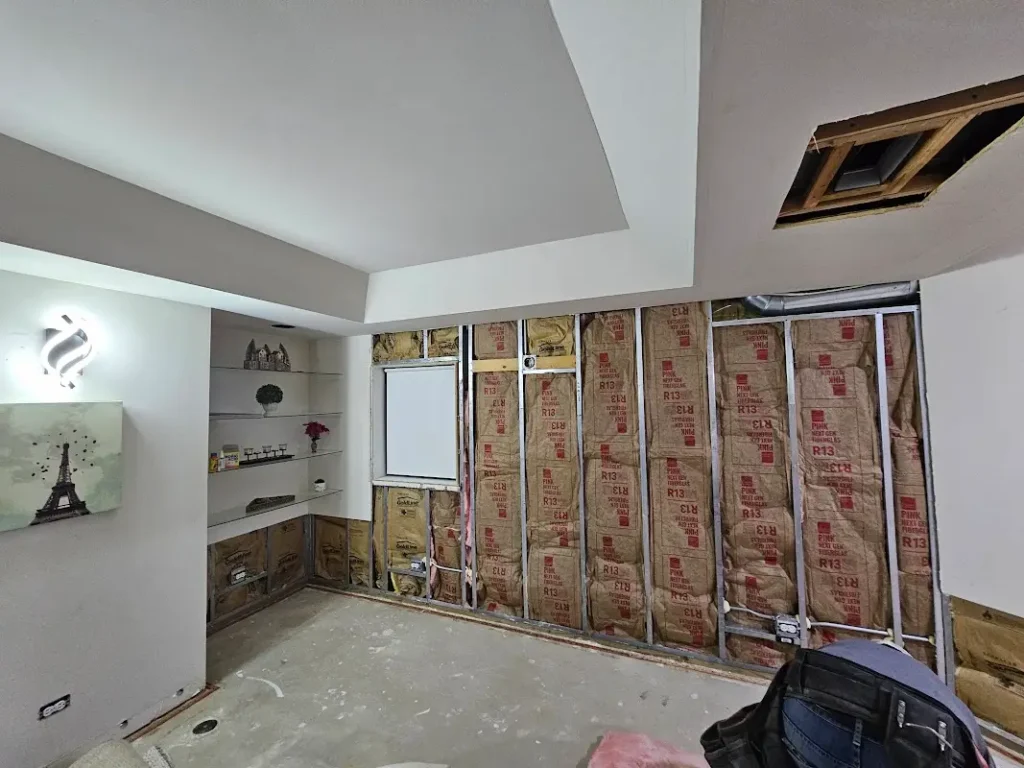 Flood damage restoration in progress showing exposed insulation, water damage repair, and drywall removal in Aurora home with tray ceiling details