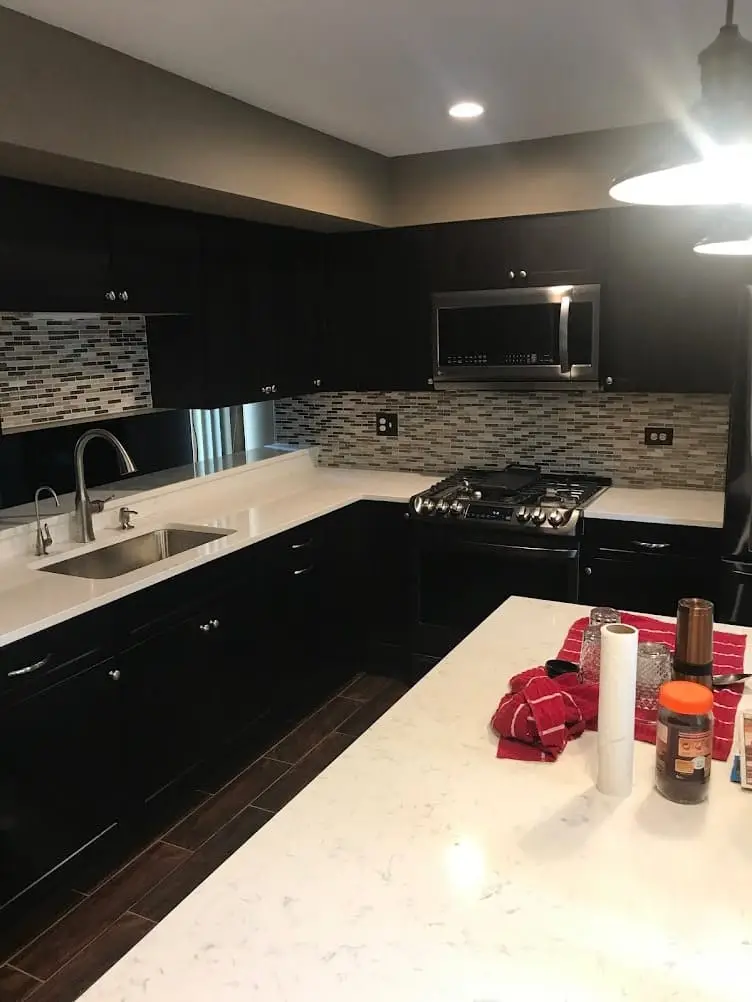 Luxury modern kitchen featuring matte black cabinets contrasting with bright white quartz countertops