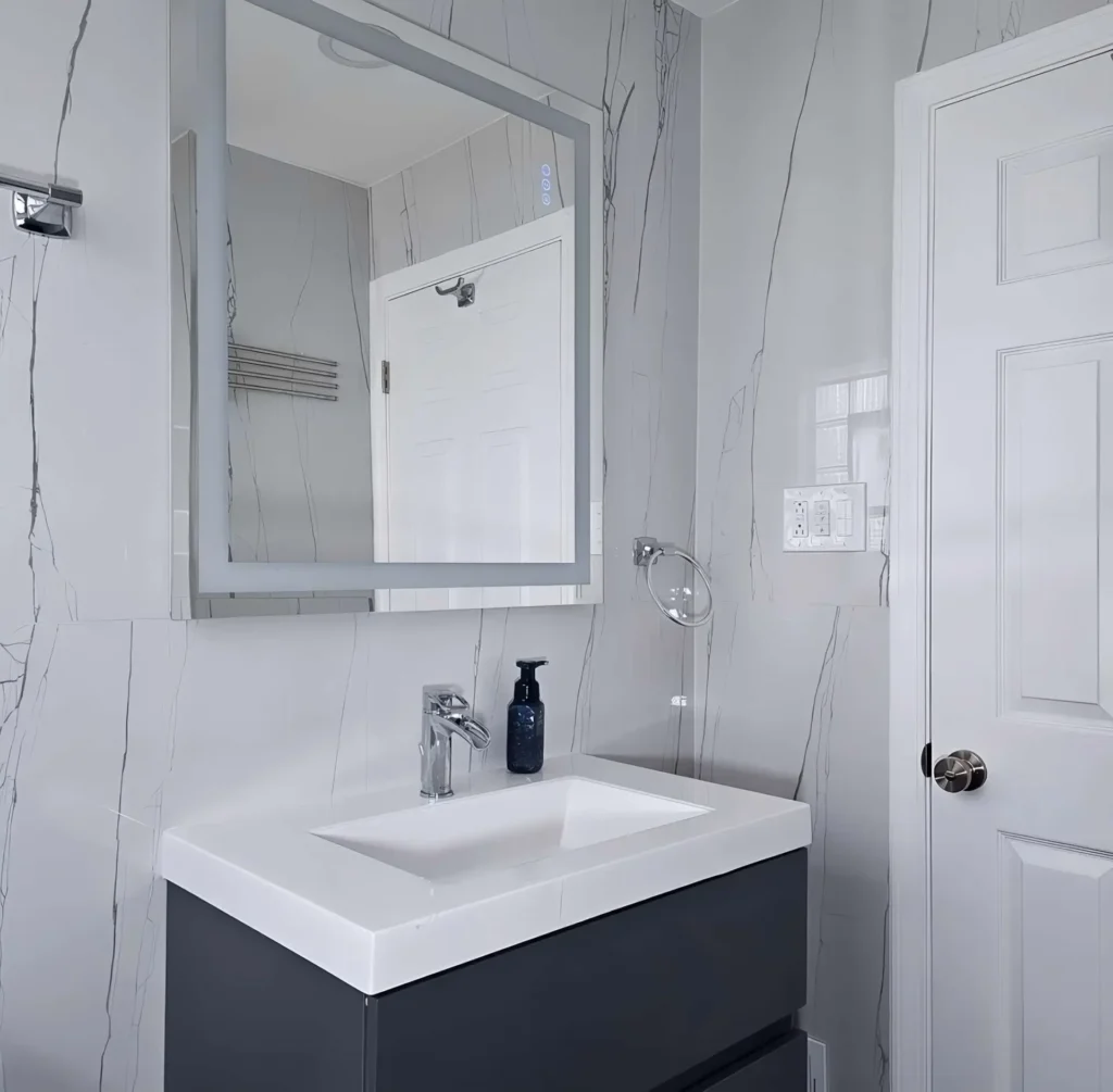 Modern floating vanity installation Chicago - luxury basement bathroom renovation featuring LED mirror, marble-effect walls, and designer fixtures in Cook County