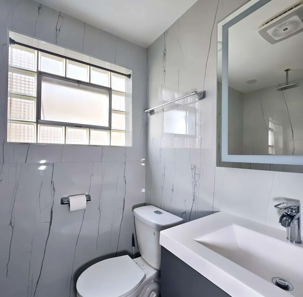 Chicago basement bathroom renovation with mold-resistant marble walls, waterproof fixtures, and glass block window - complete moisture control solutions in Cook County
