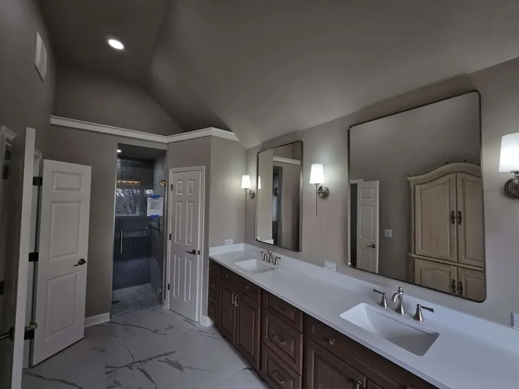 Modern bathroom featuring professional paint finishes in warm gray, crisp white trim, vaulted ceiling, and expert crown molding work by Chicagoland painting contractor