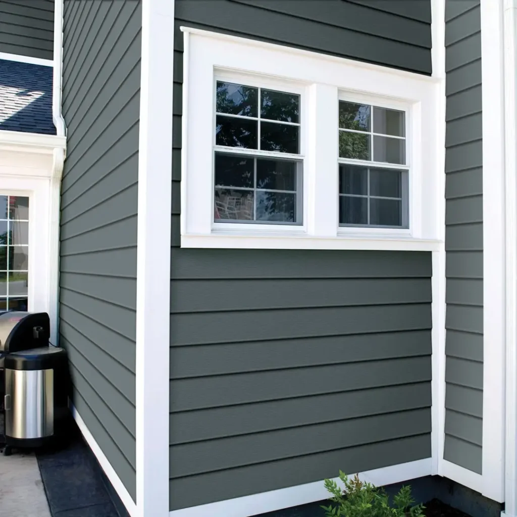 Double-hung white windows with trim installed on dark gray siding, showing professional window replacement
